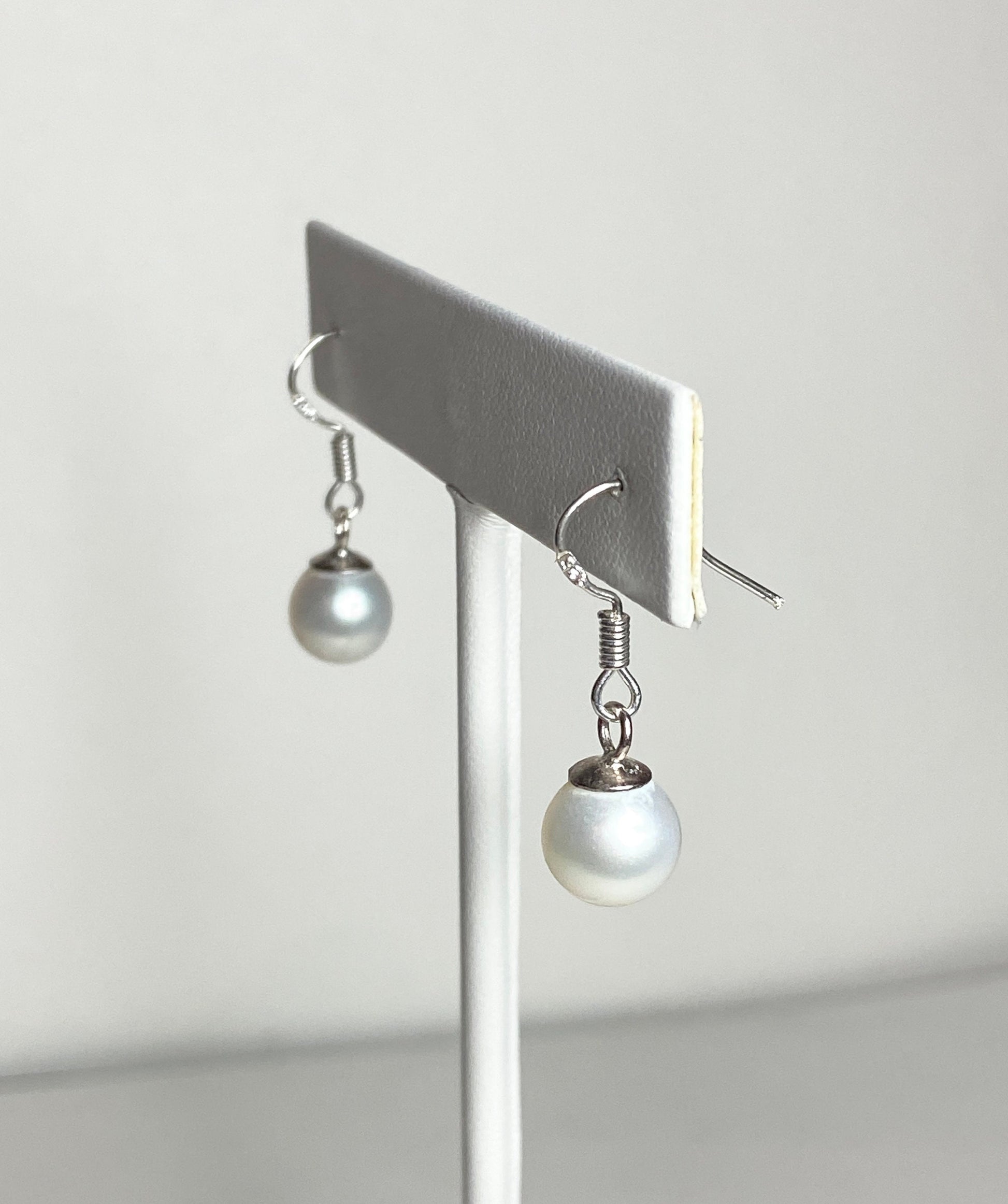 Sterling silver dangle earrings with 8mm white freshwater pearls.