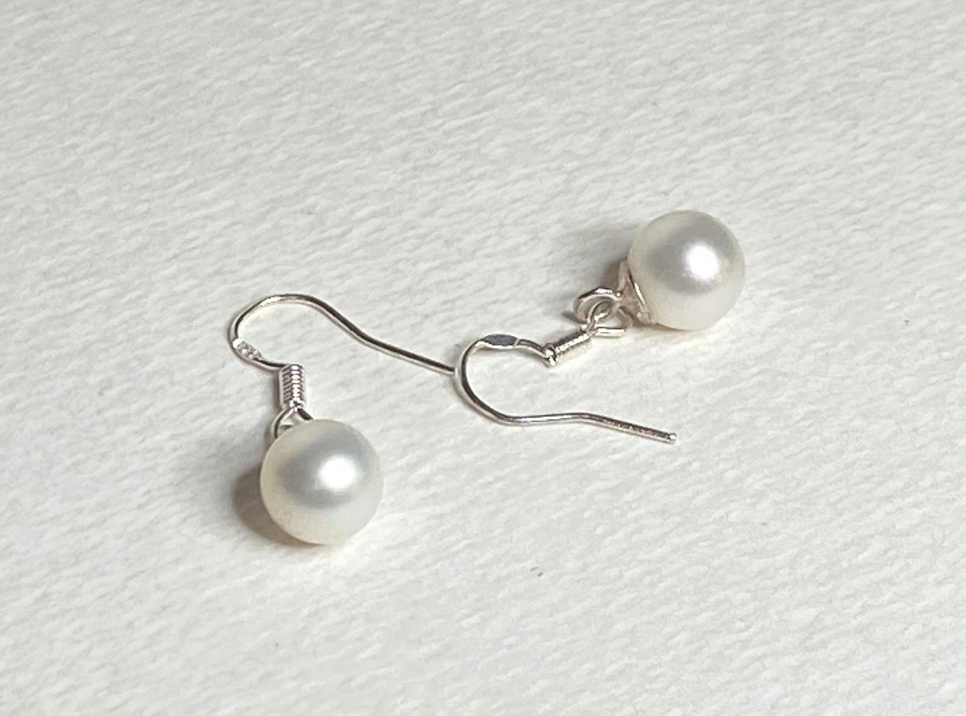 Sterling silver dangle earrings with 8mm white freshwater pearls.