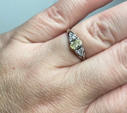 A 14k gold ring with a light yellow oval diamond and white side diamonds.