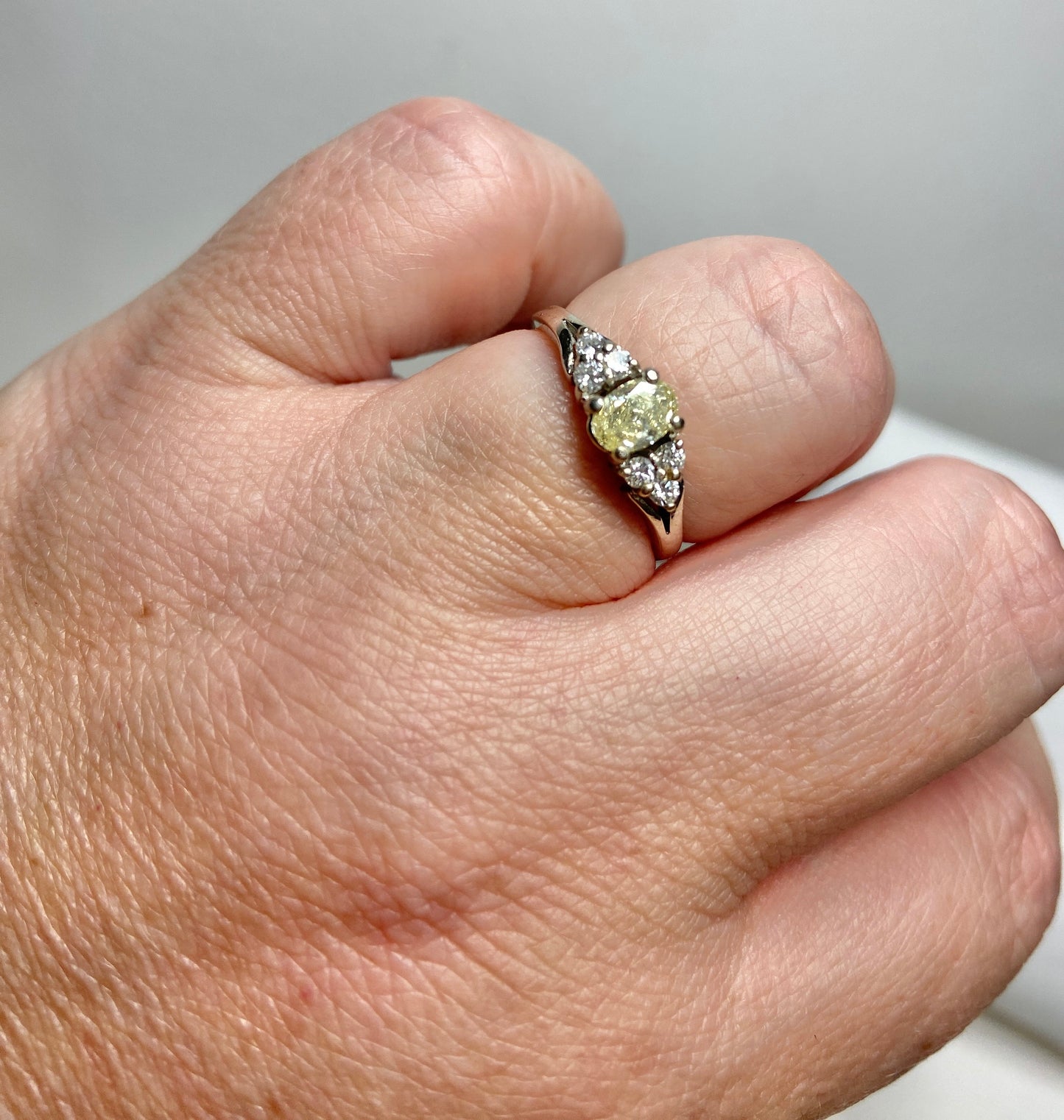 A 14k gold ring with a light yellow oval diamond and white diamonds.