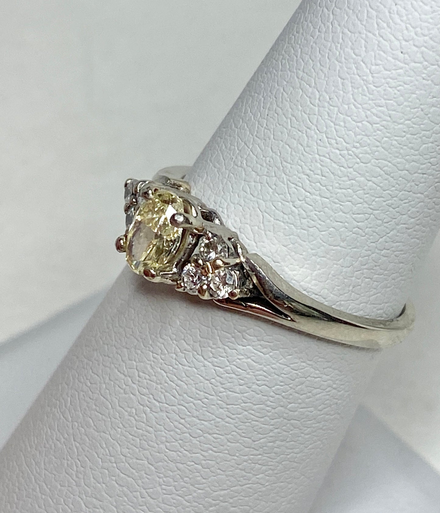 A 14k gold ring with a light yellow oval diamond and white side diamonds.