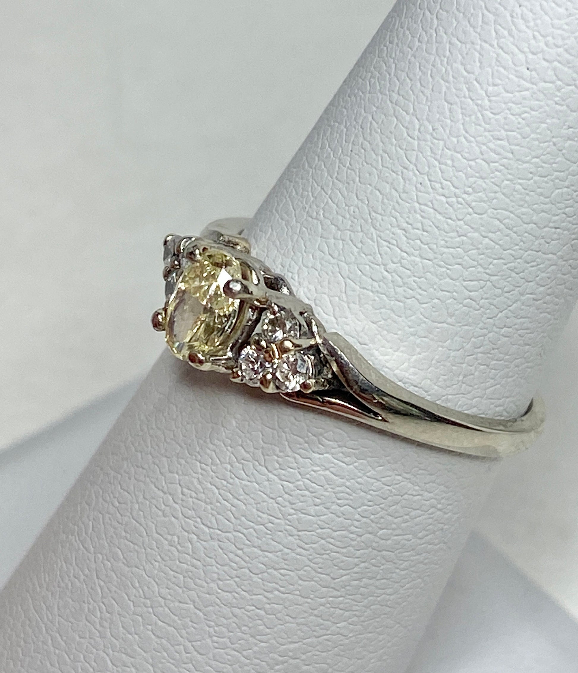 A 14k gold ring with a light yellow oval diamond and white side diamonds.