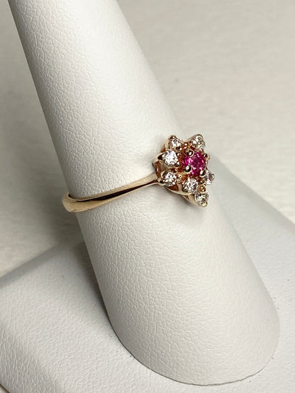 A 14k gold ring with a central rubellite tourmaline surrounded by diamonds.