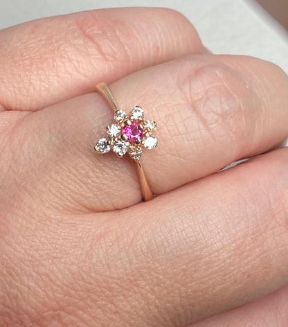 A 14k gold ring with a central rubellite tourmaline surrounded by diamonds.