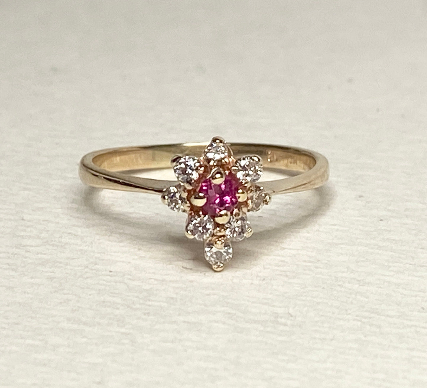 A 14k gold ring with a central rubellite tourmaline surrounded by diamonds.