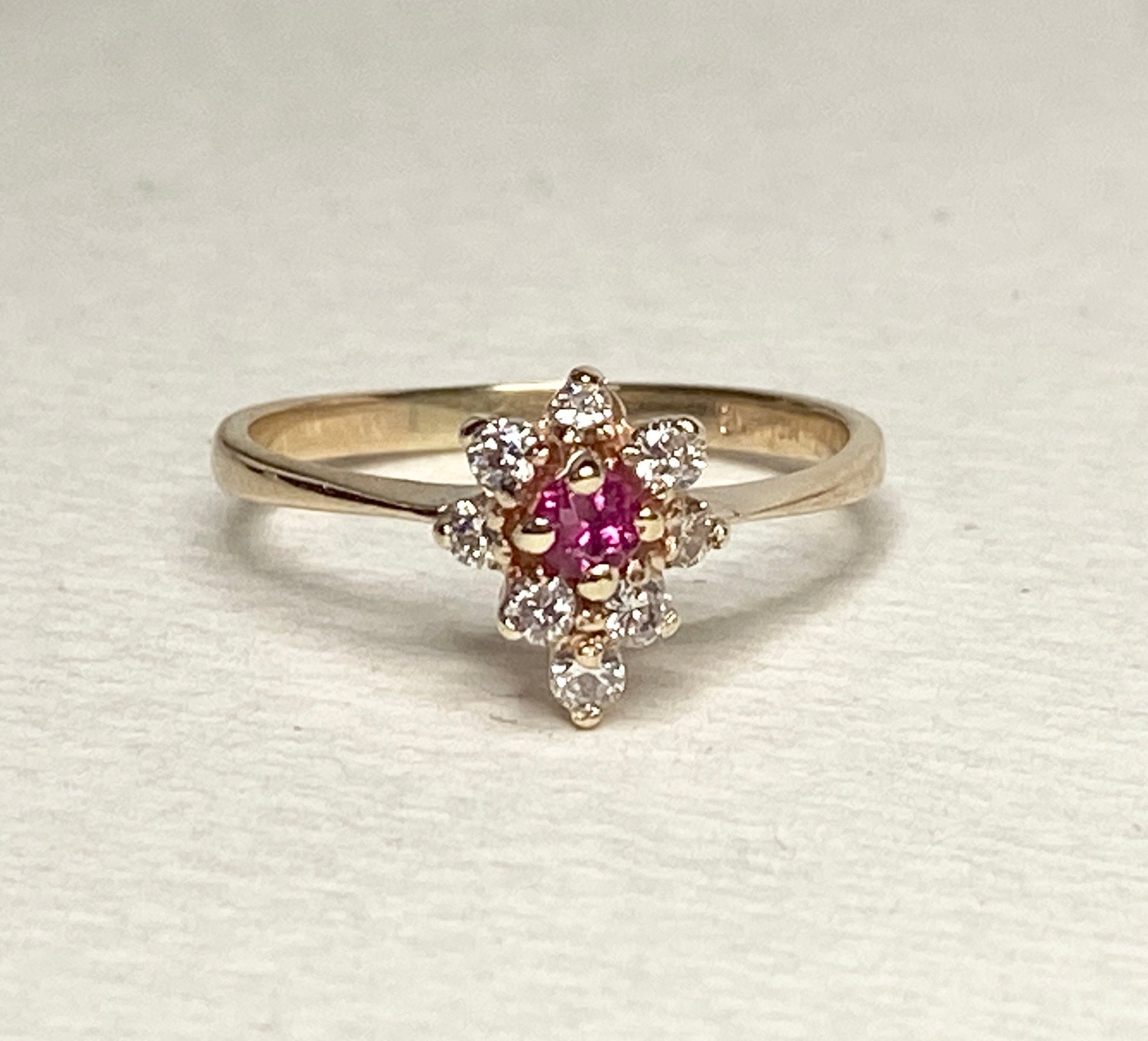 A 14k gold ring with a central rubellite tourmaline surrounded by diamonds.