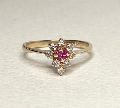 A 14k gold ring with a central rubellite tourmaline surrounded by diamonds.