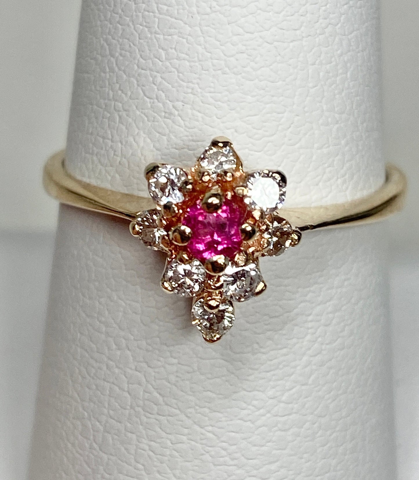 A 14k gold ring with a rubellite tourmaline center and surrounding diamonds.