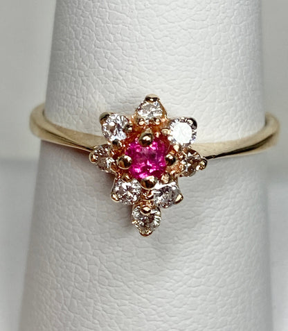 A 14k gold ring with a rubellite tourmaline center and surrounding diamonds.