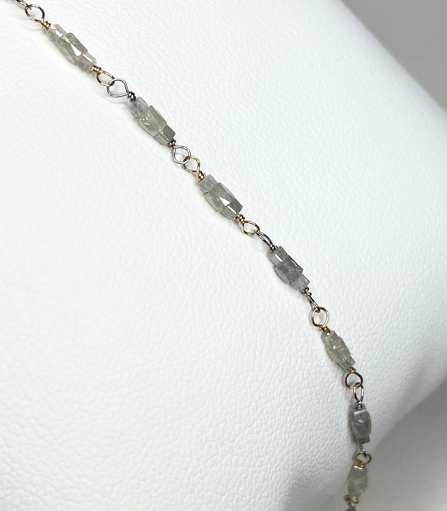 A bracelet with faceted diamond beads and gold links.
