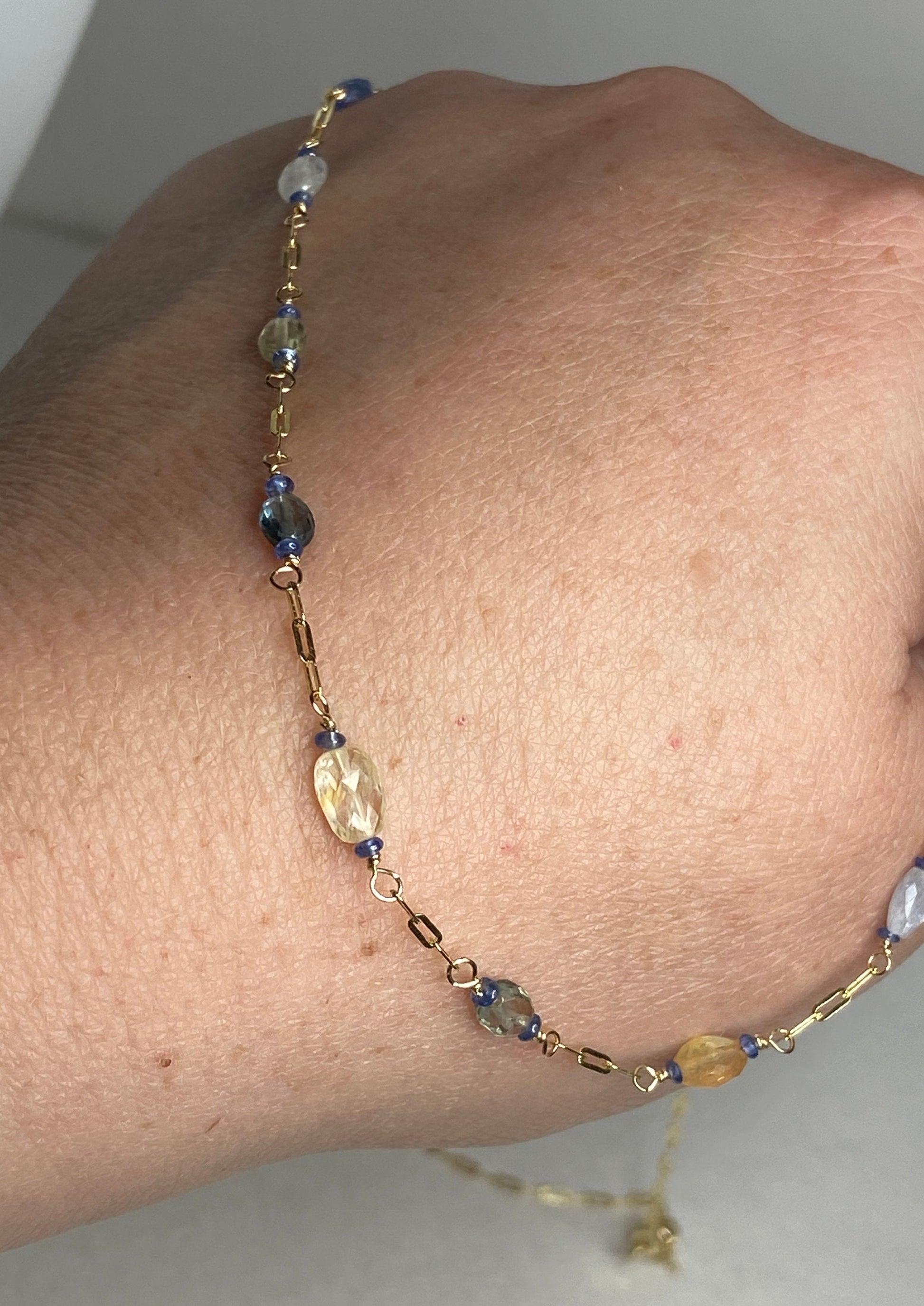 A 14k gold station chain necklace with multi-colored sapphires.