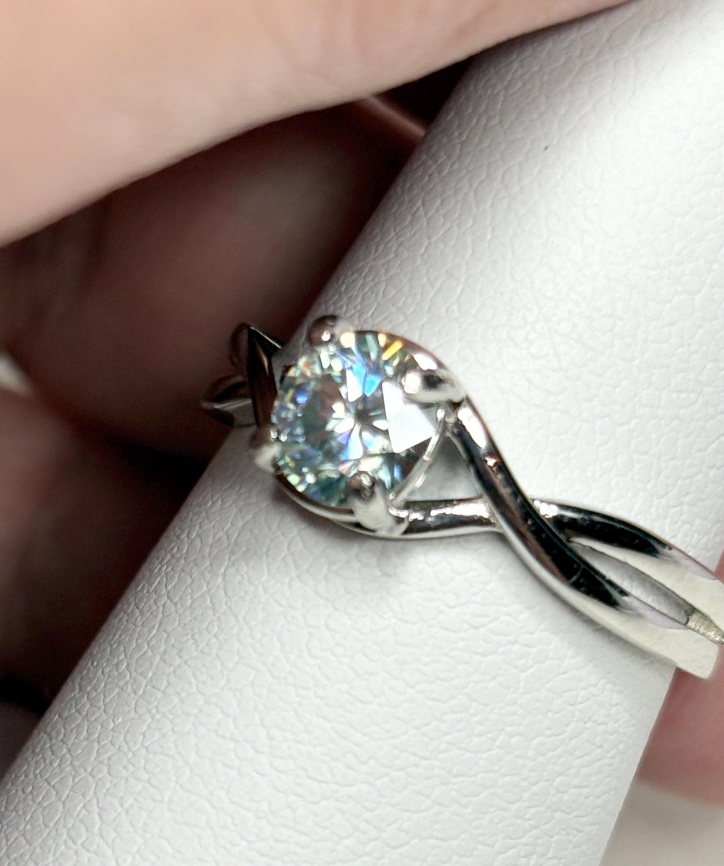 Sterling silver ring with a light greenish-blue moissanite solitaire.