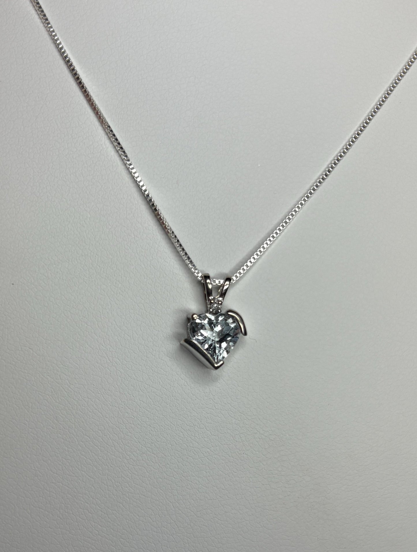 A heart-shaped aquamarine pendant with a diamond on a silver chain.