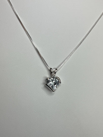 A heart-shaped aquamarine pendant with a diamond on a silver chain.