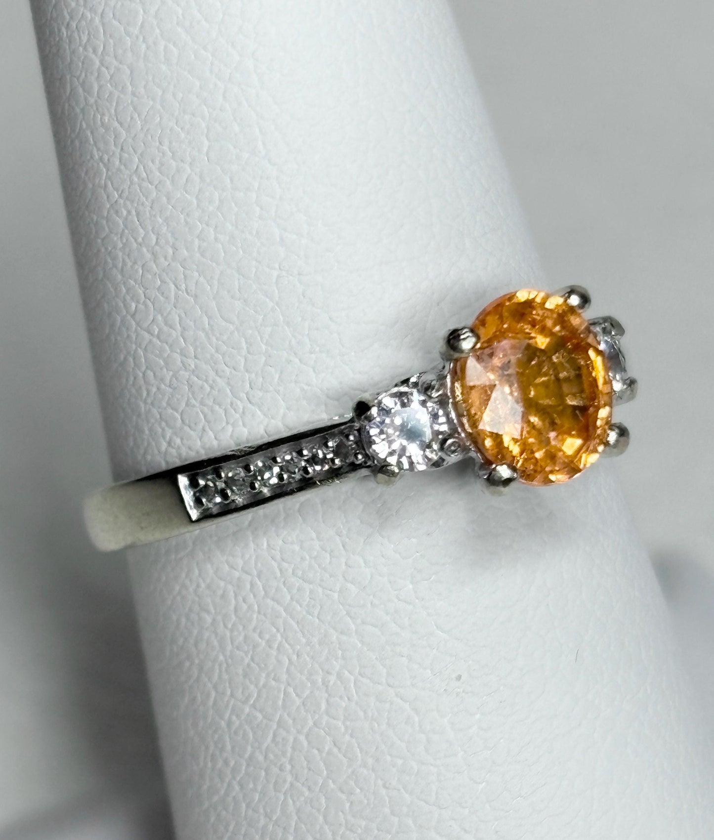 A 10k white gold ring with an oval orange spessartite garnet and accent diamonds.