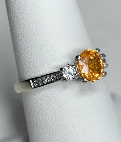A 10k white gold ring with an oval orange spessartite garnet and accent diamonds.
