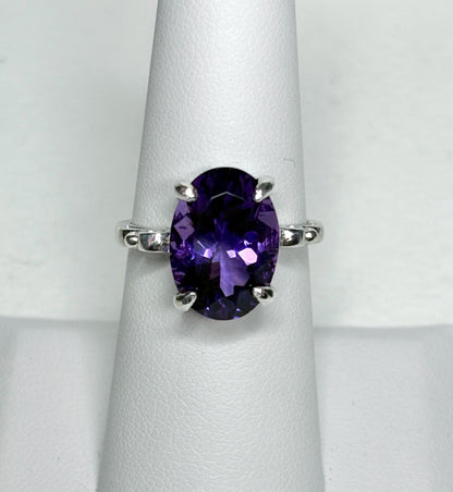 Sterling silver ring with a large oval amethyst gemstone and scroll swirl details.