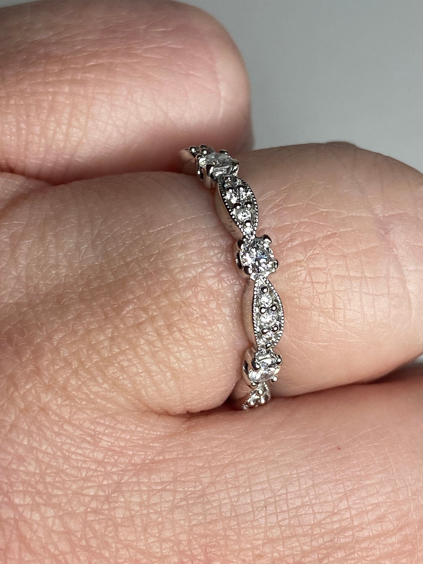 A delicate 10k white gold band ring with small diamonds and milgrain detailing.