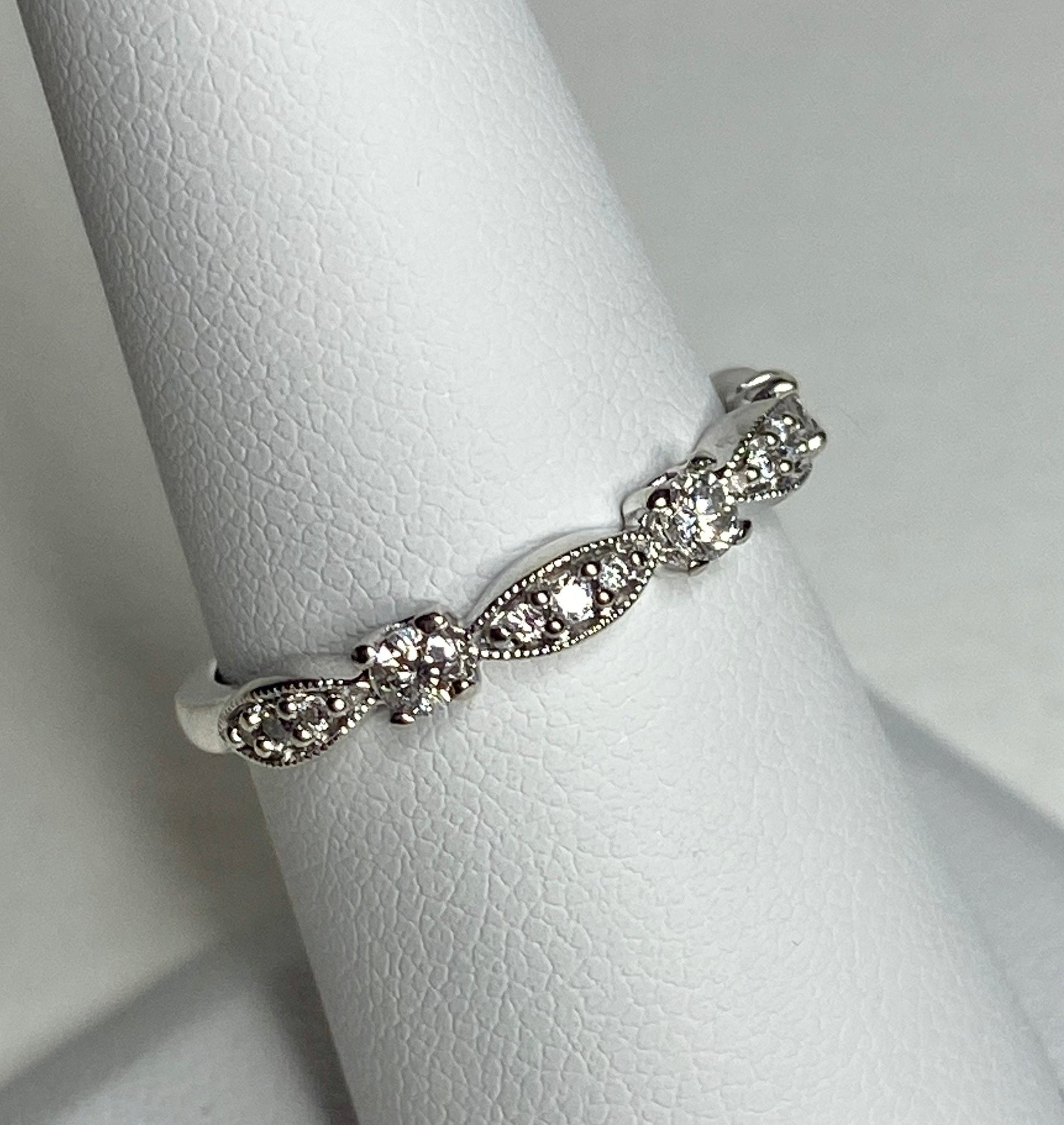 A delicate 10k white gold band ring with small diamonds and milgrain detailing.