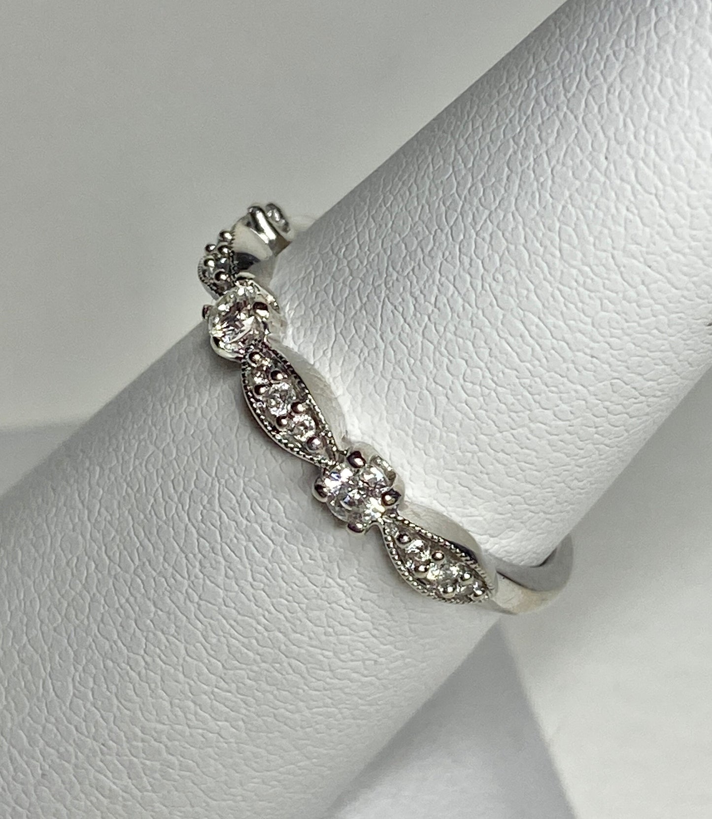 A delicate 10k white gold band ring with milgrain detailing and small diamonds.