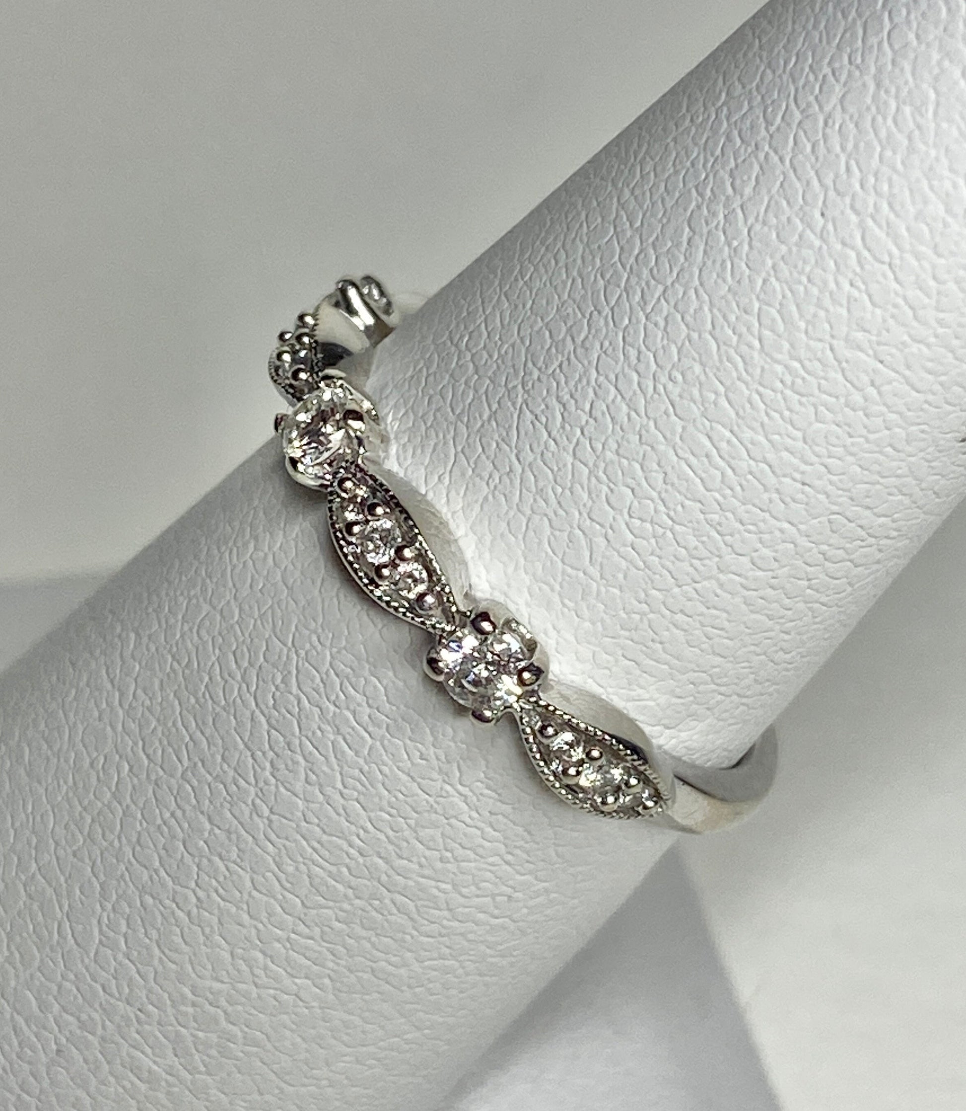 A delicate 10k white gold band ring with milgrain detailing and small diamonds.