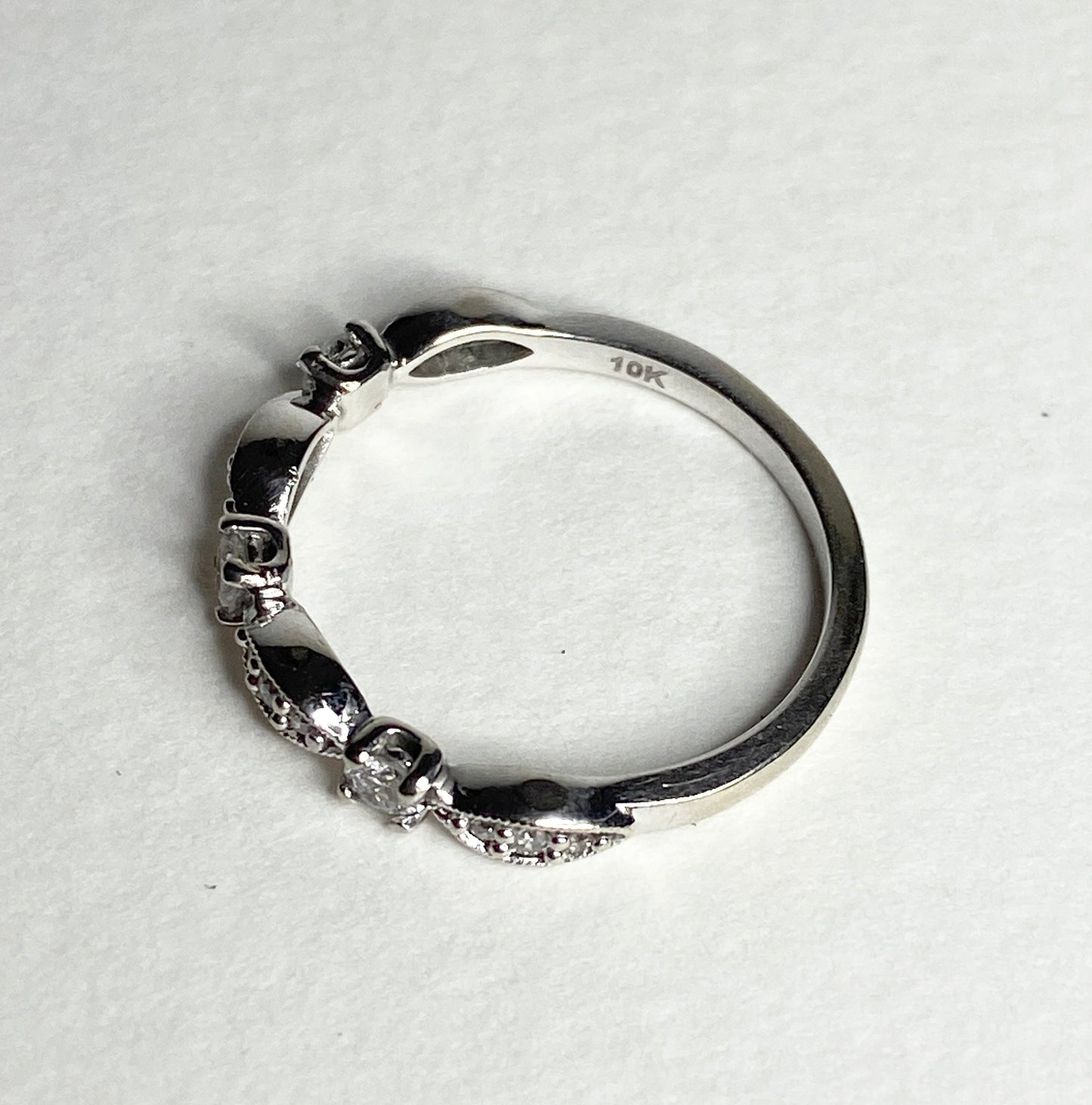 A 10k white gold diamond band ring with milgrain detailing.