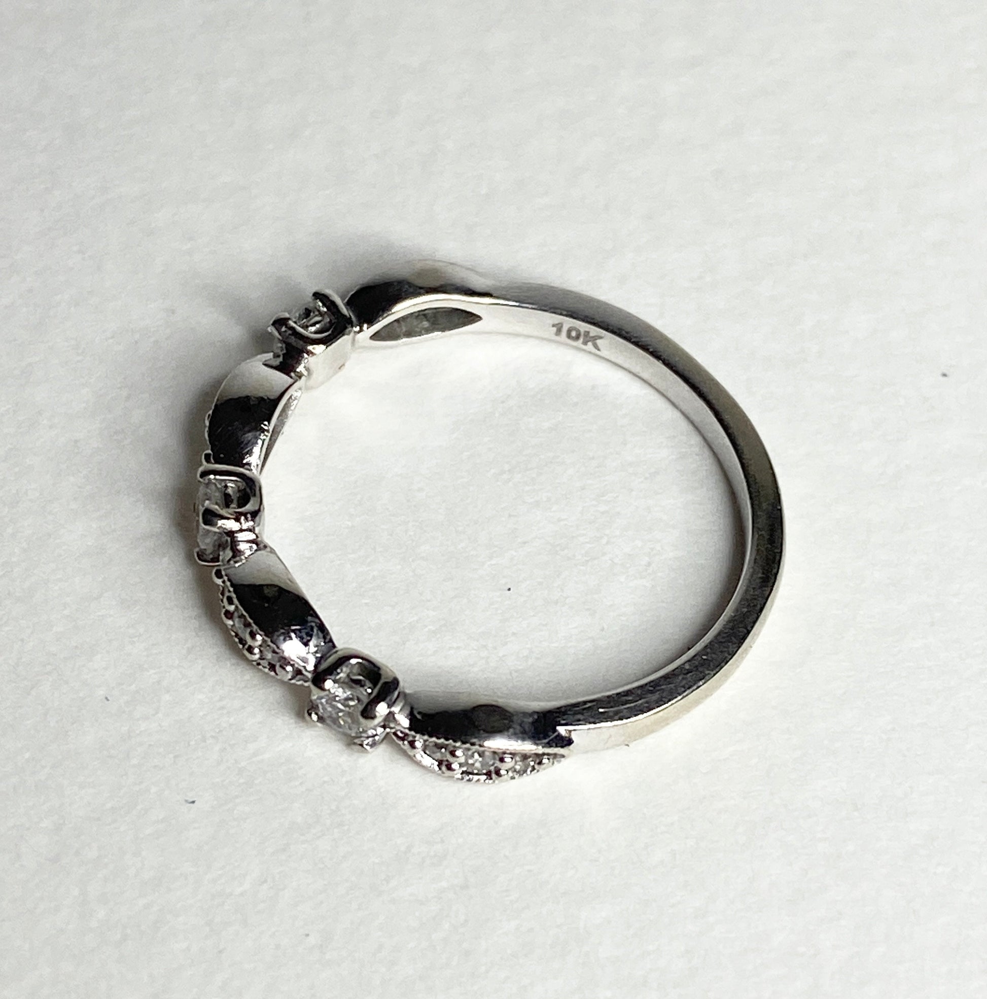 A 10k white gold diamond band ring with milgrain detailing.