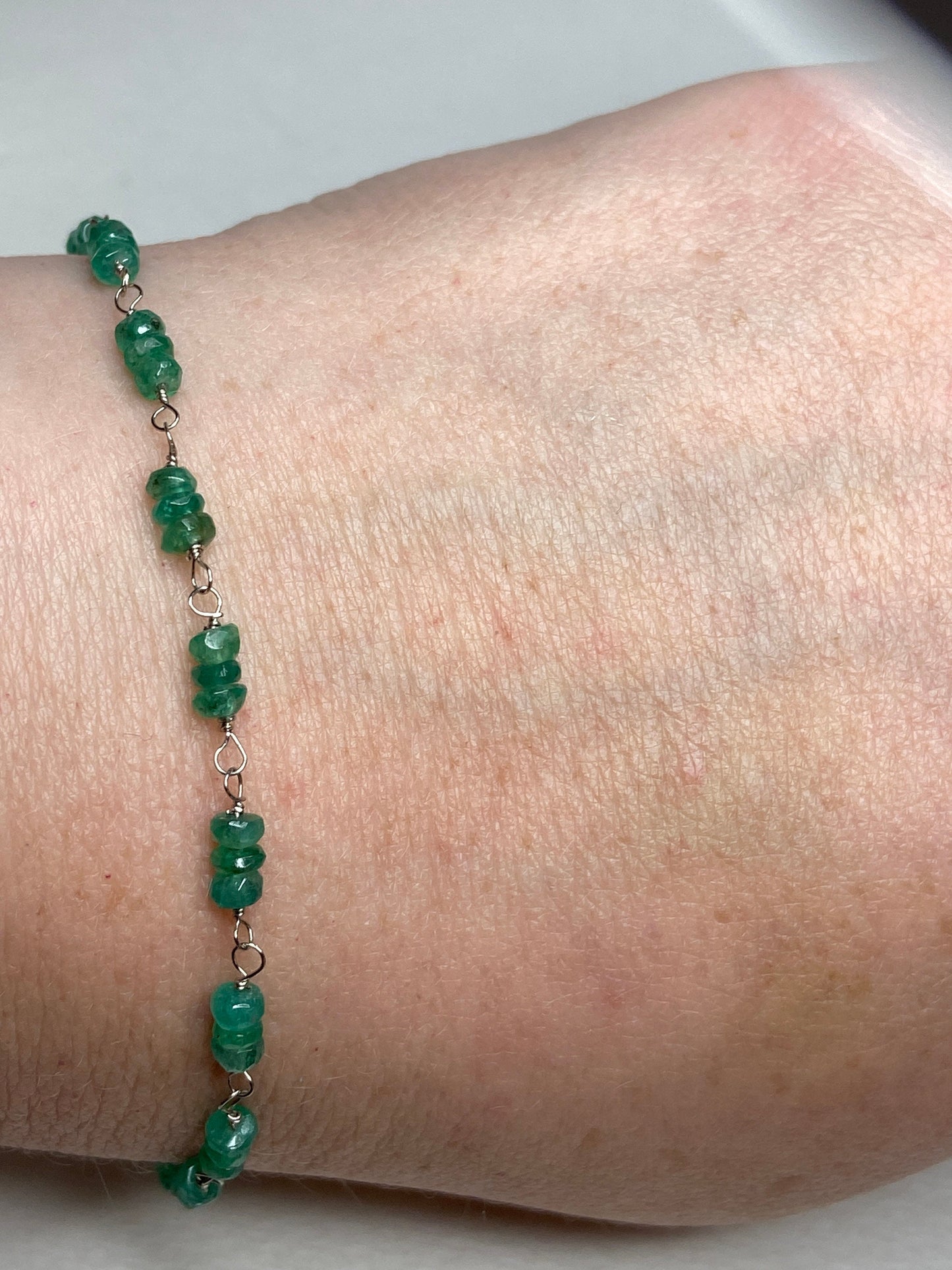 A bracelet with natural emerald beads strung on white gold wire.