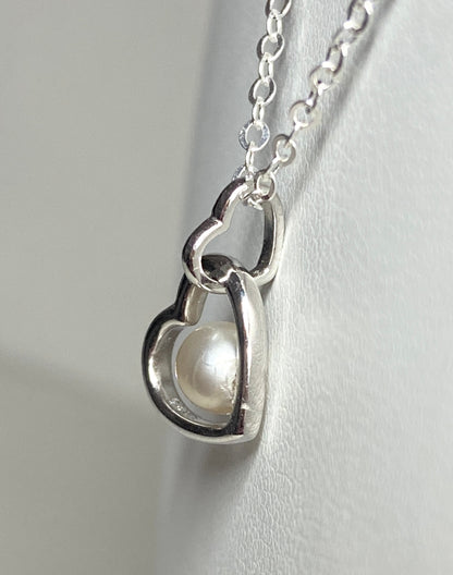 Sterling silver necklace with a double heart pendant holding a 5mm cultured akoya pearl.