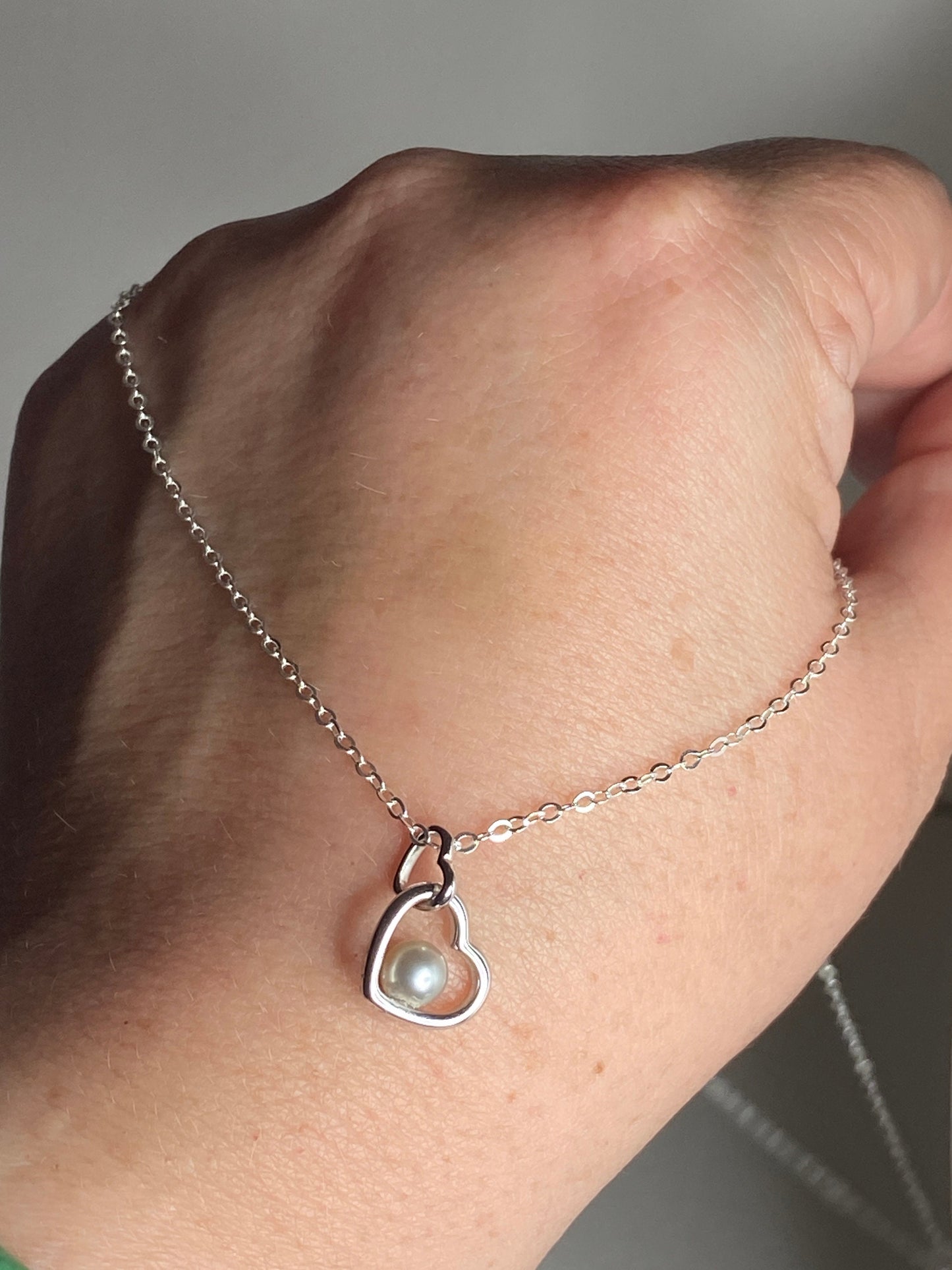 Sterling silver necklace with a double heart pendant and a 5mm akoya pearl.