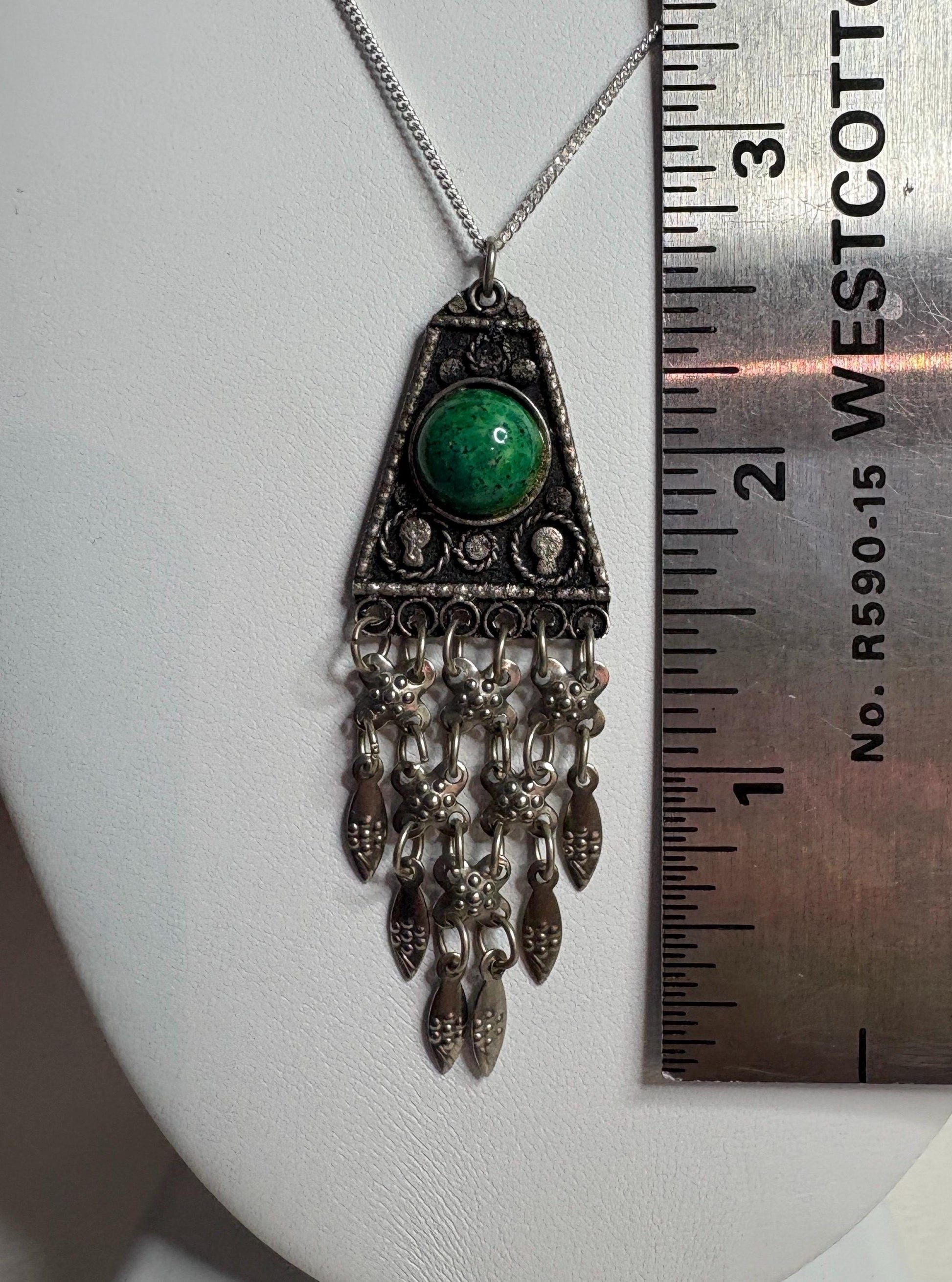 Sterling silver pendant with green stone and fringe detail.