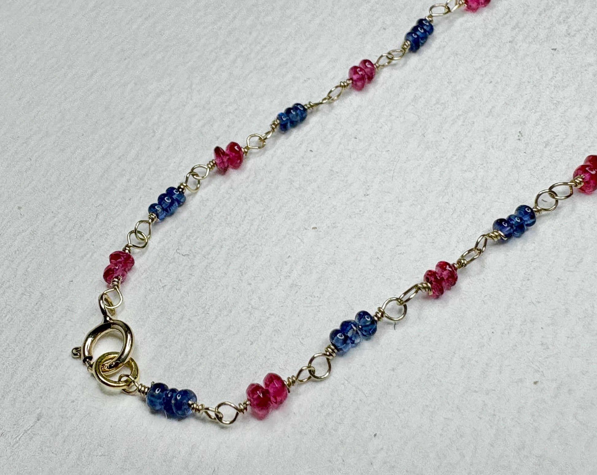 Dainty 14k gold bracelet with smooth sapphire and red spinel beads.