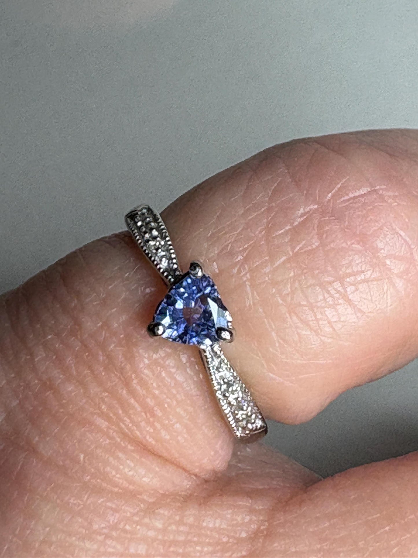 Tanzanite trillion ring with diamonds on a white gold band.