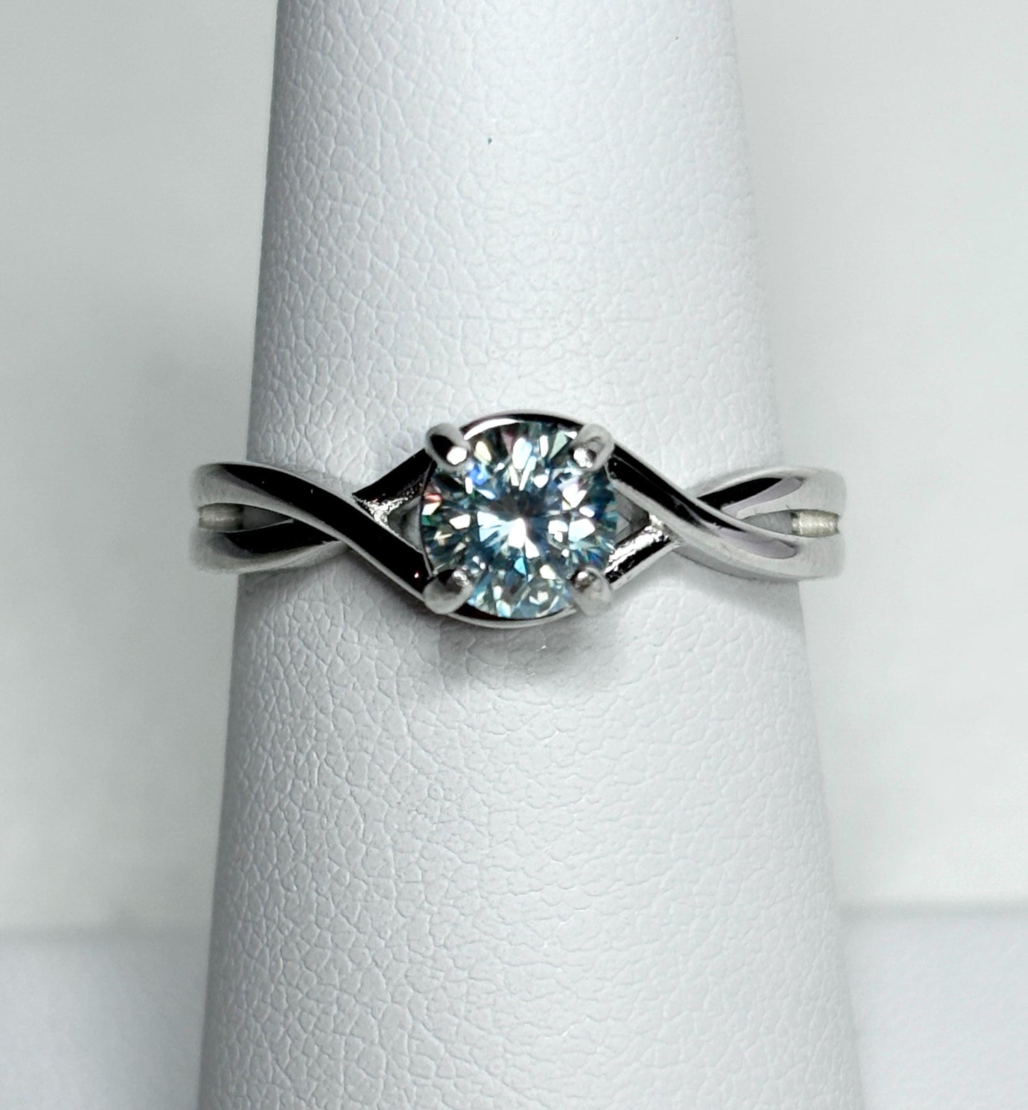 Sterling silver bypass ring with a light greenish-blue moissanite solitaire.