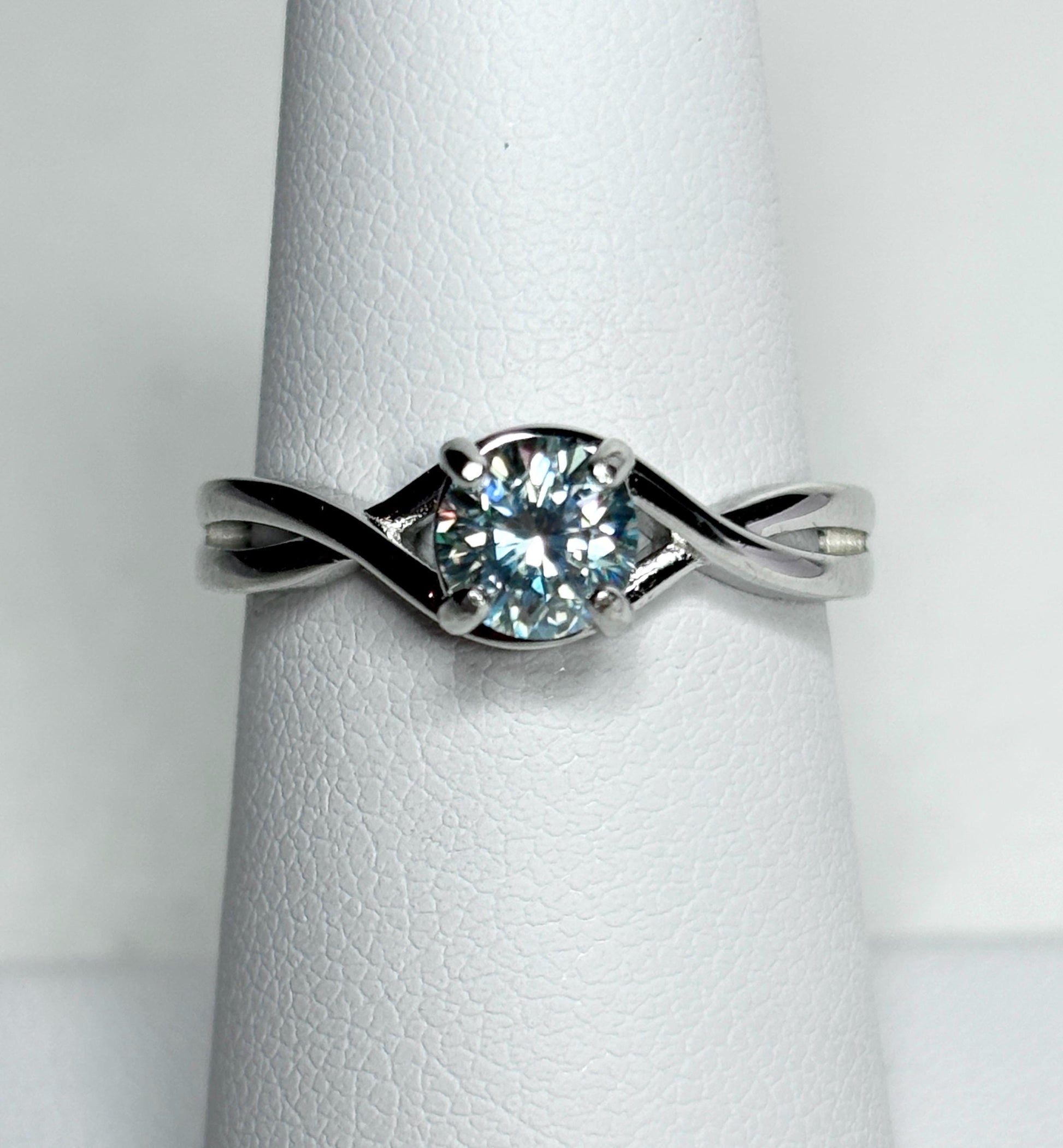 Sterling silver bypass ring with a light greenish-blue moissanite solitaire.