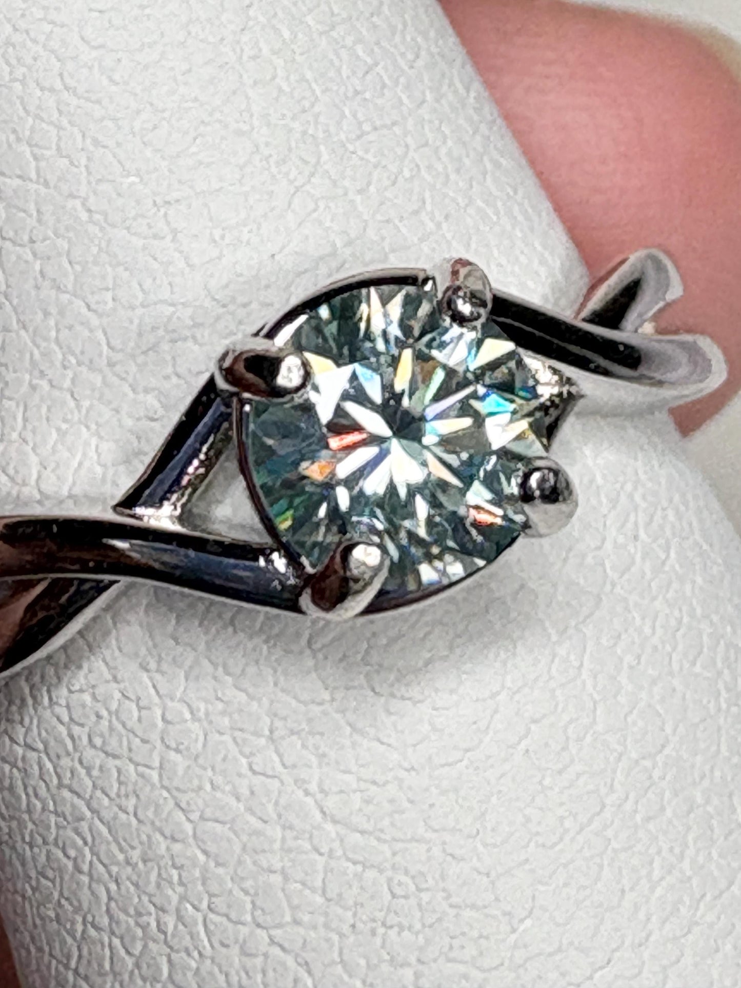 Sterling silver ring with a light greenish-blue moissanite solitaire.