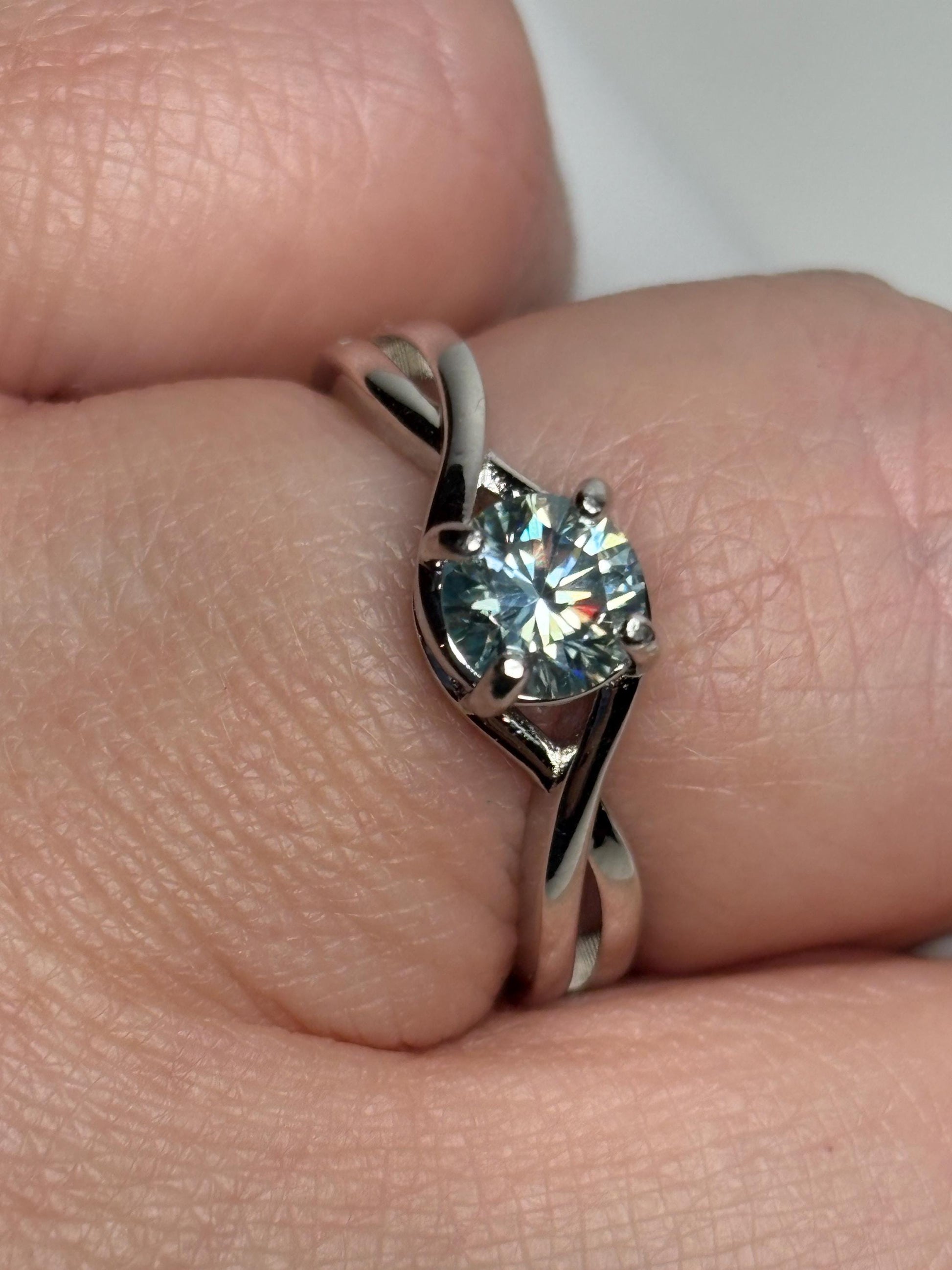 Sterling silver ring with a light greenish-blue moissanite solitaire.
