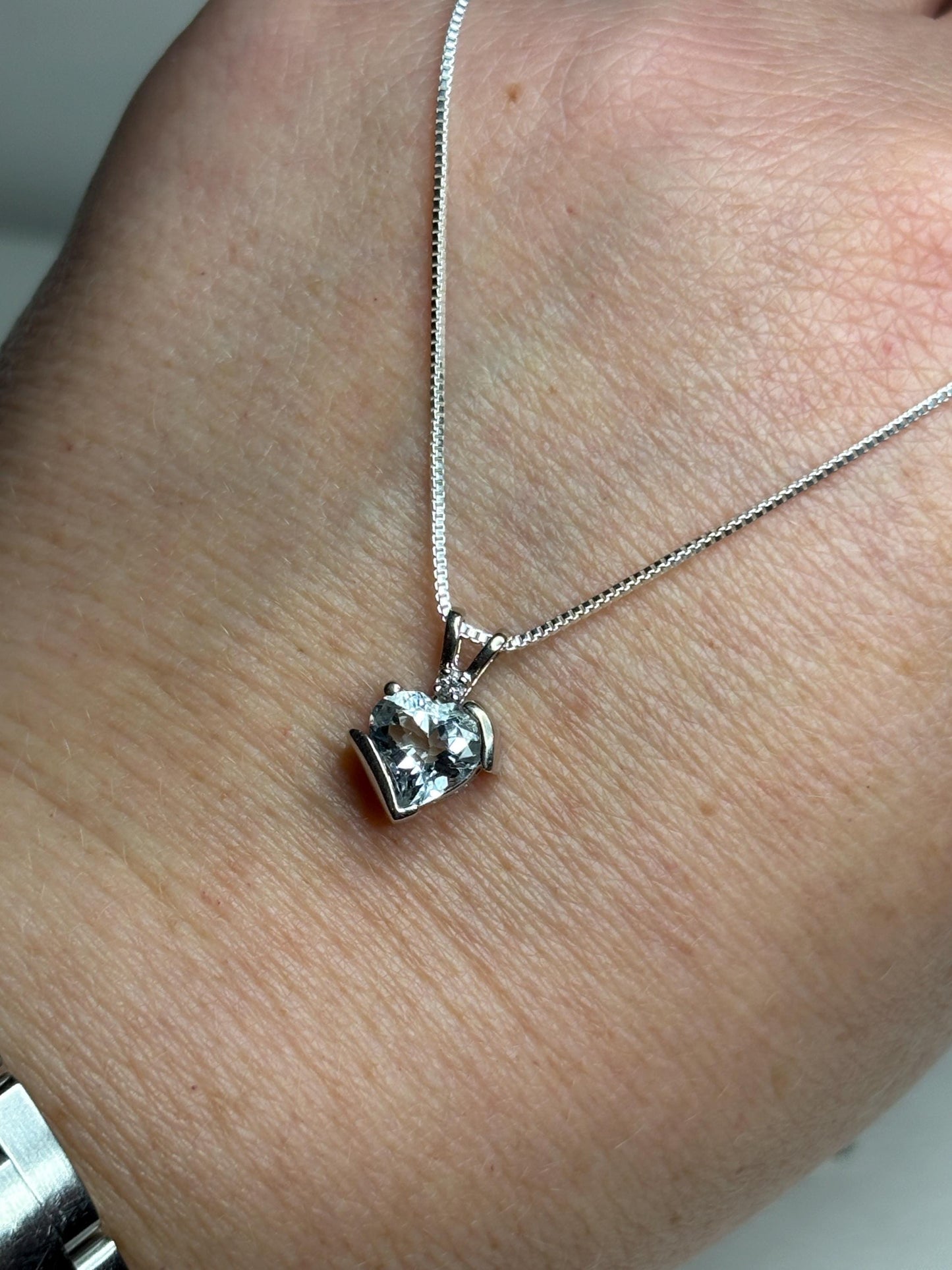 A 10k white gold heart pendant with an aquamarine and diamond on a sterling silver chain.