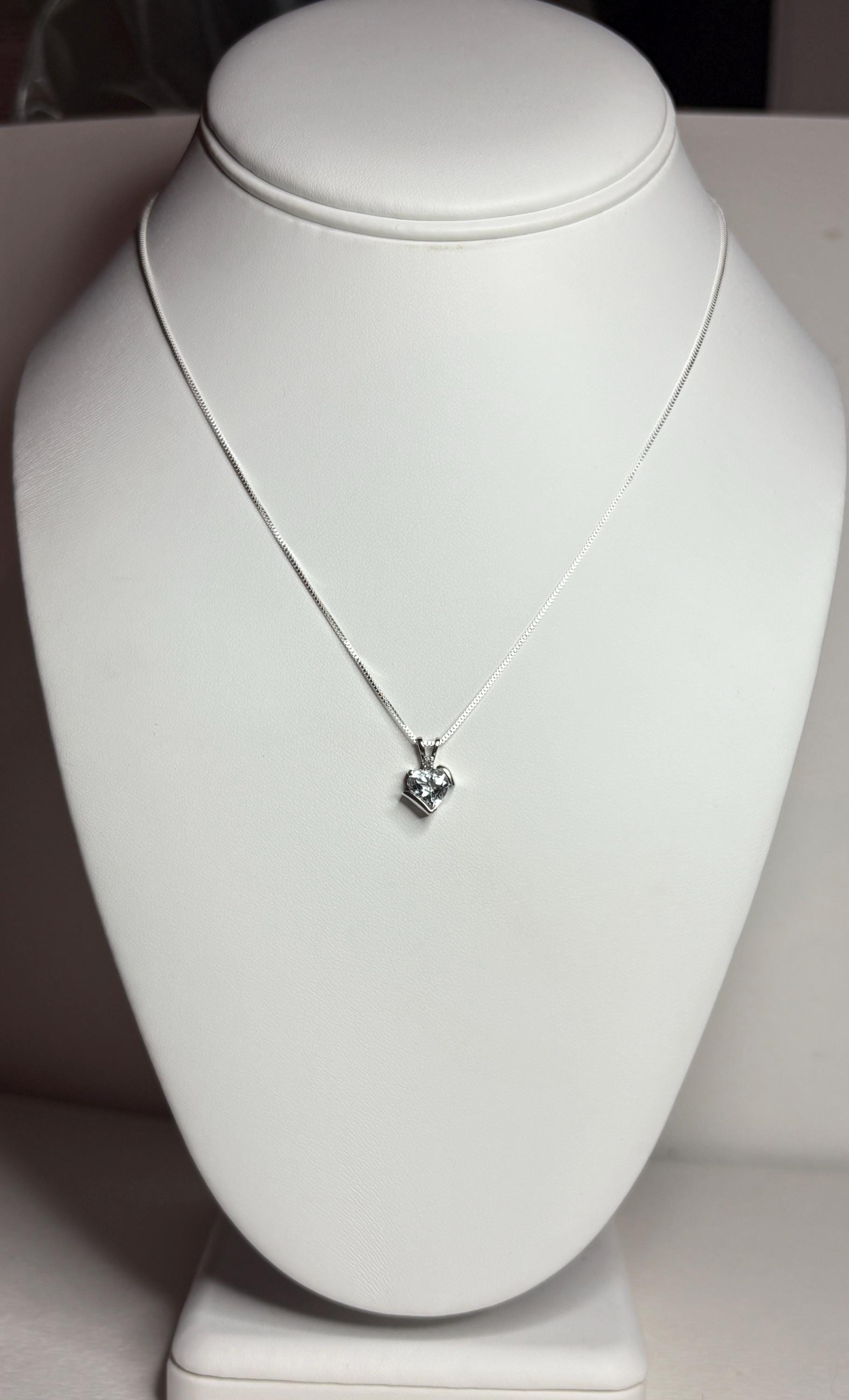 A white gold heart pendant with an aquamarine and diamond on a silver chain.