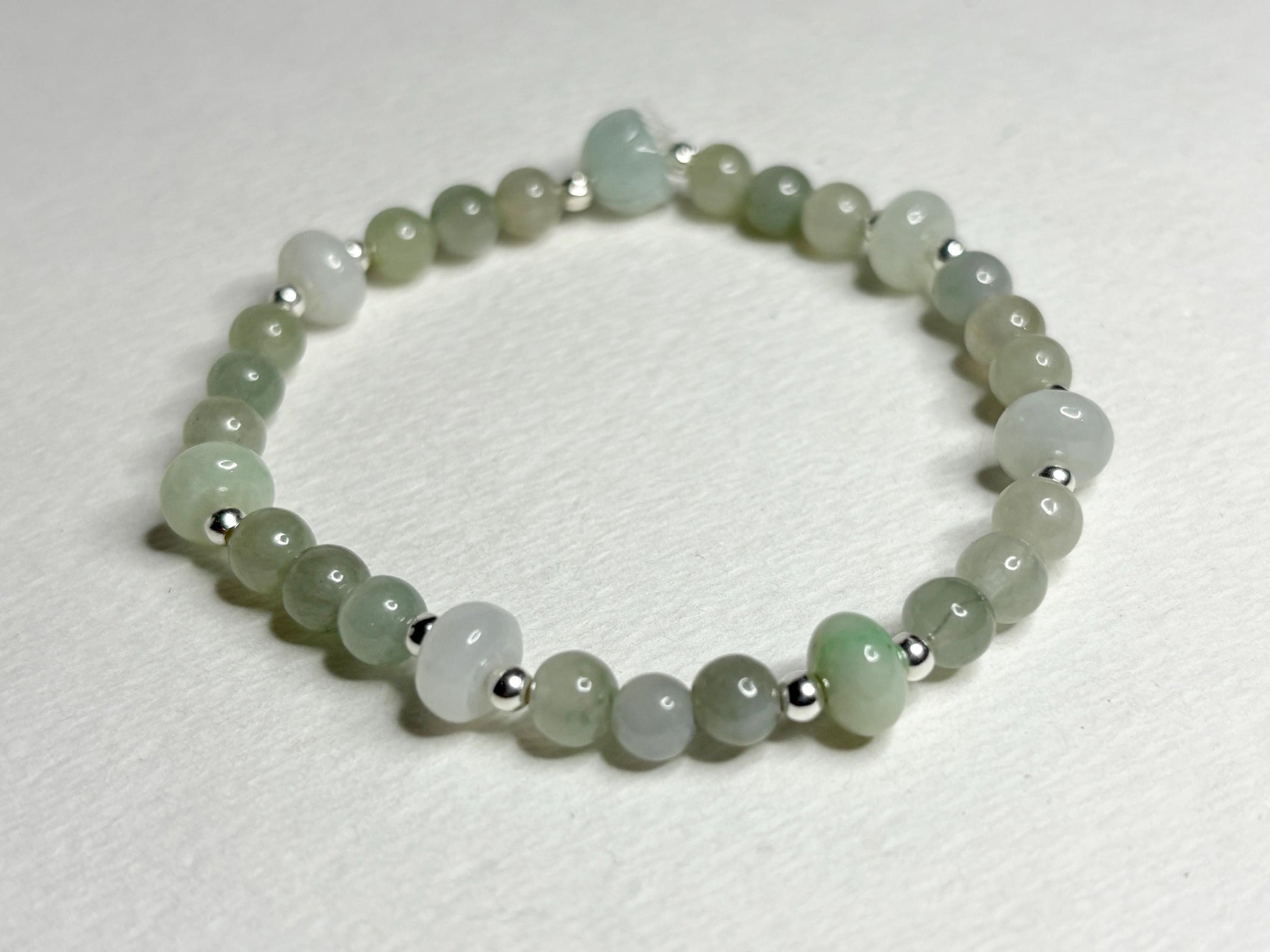 A natural Type A icy Burmese jadeite jade stretch bracelet with sterling silver accents.
