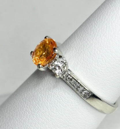 A 10k white gold ring with an oval orange spessartite garnet and accent diamonds.