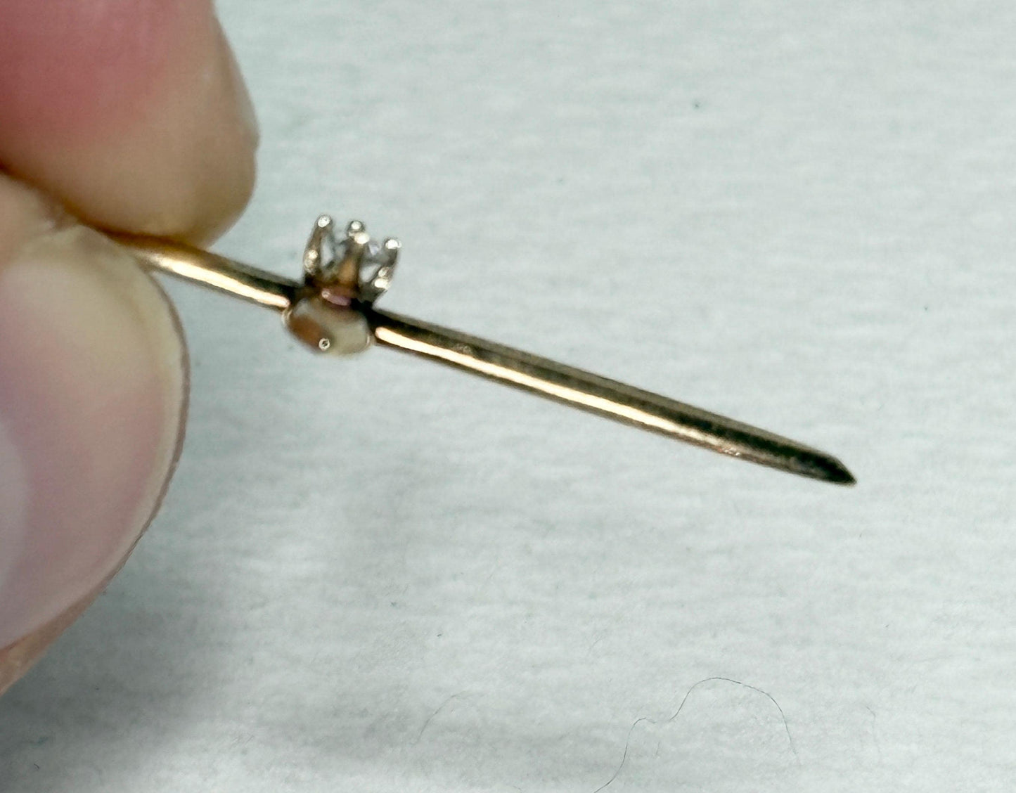 A gold cross pendant with a small diamond on a gold chain.