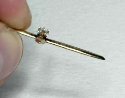 A gold cross pendant with a small diamond on a gold chain.