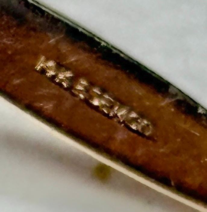 Close-up of a gold pendant with an inscription.