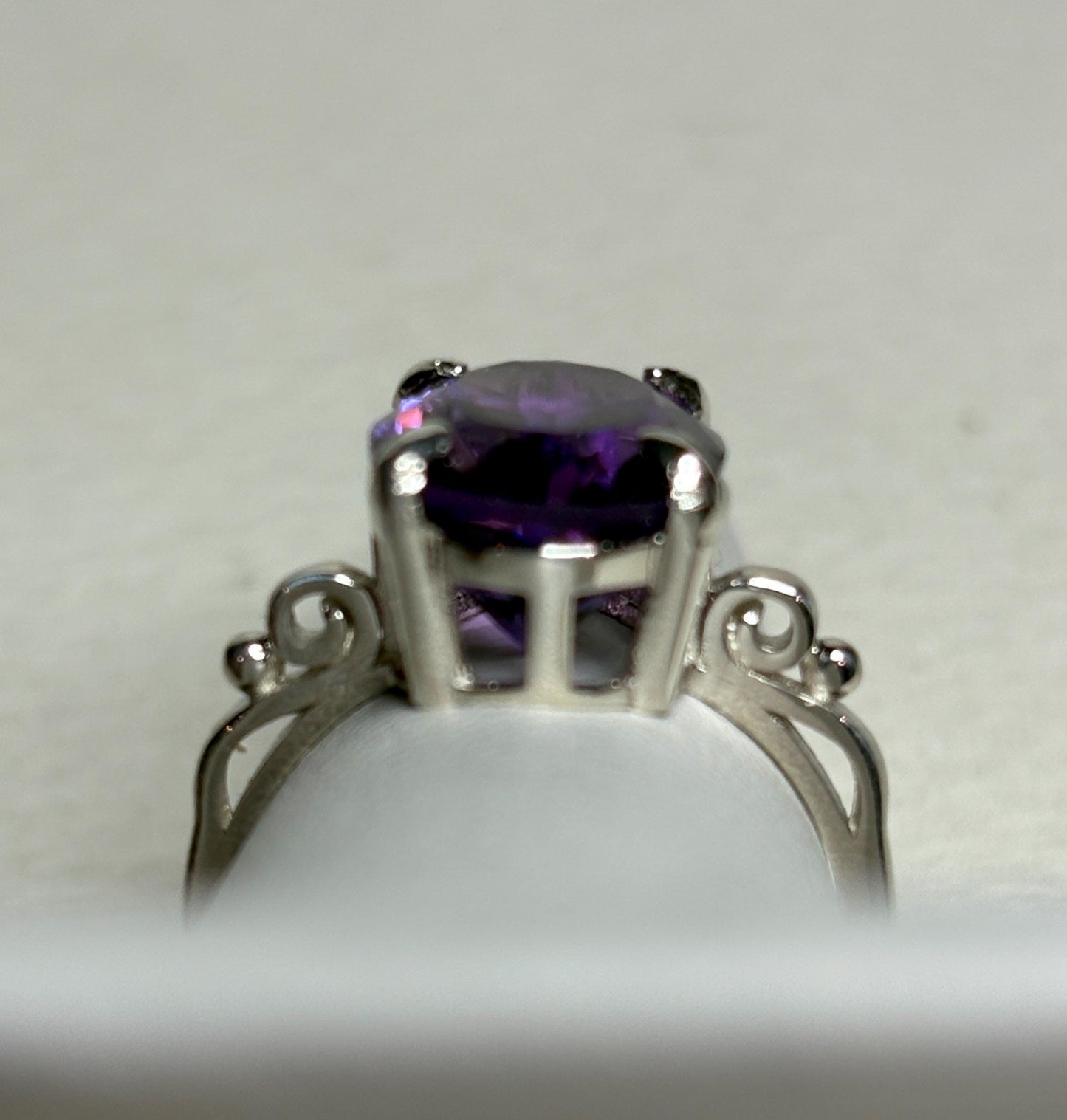 Sterling silver ring with a large oval amethyst and scroll swirl details.