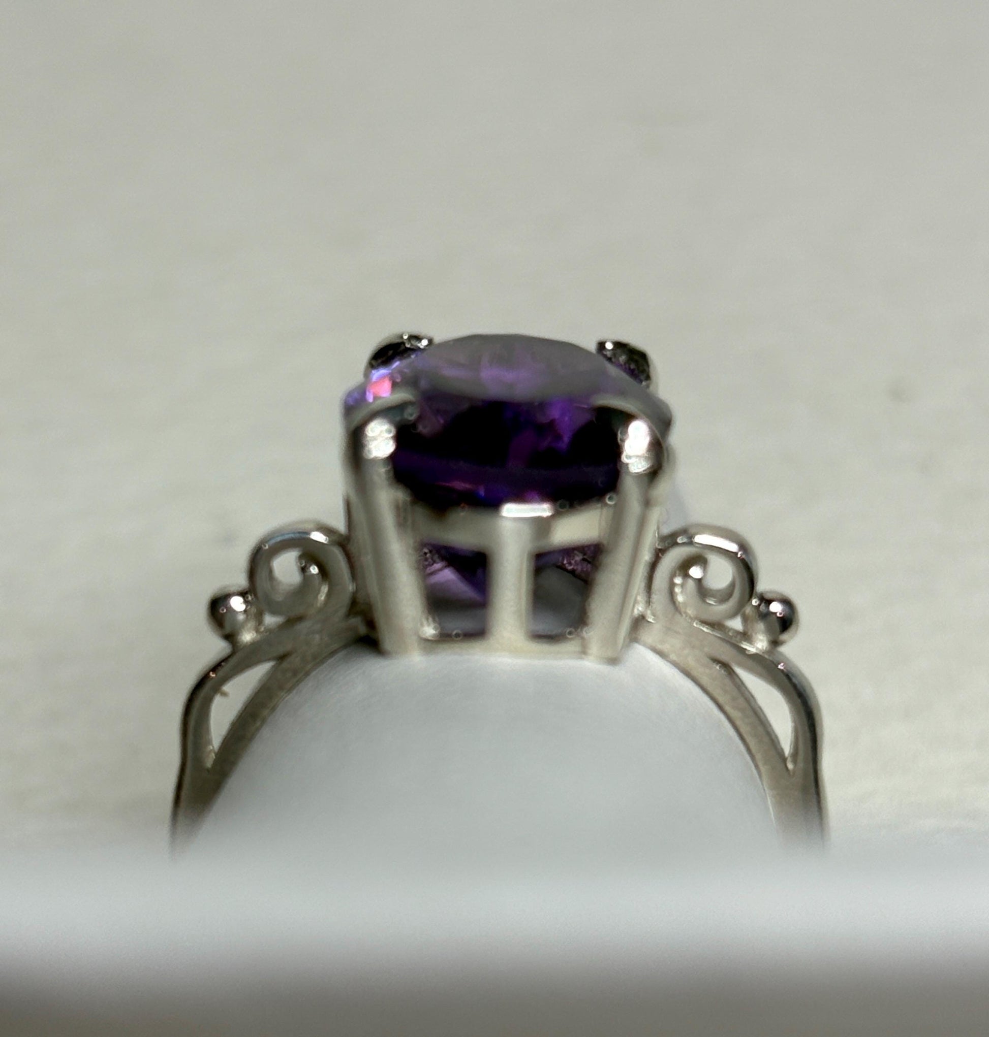 Sterling silver ring with a large oval amethyst and scroll swirl details.