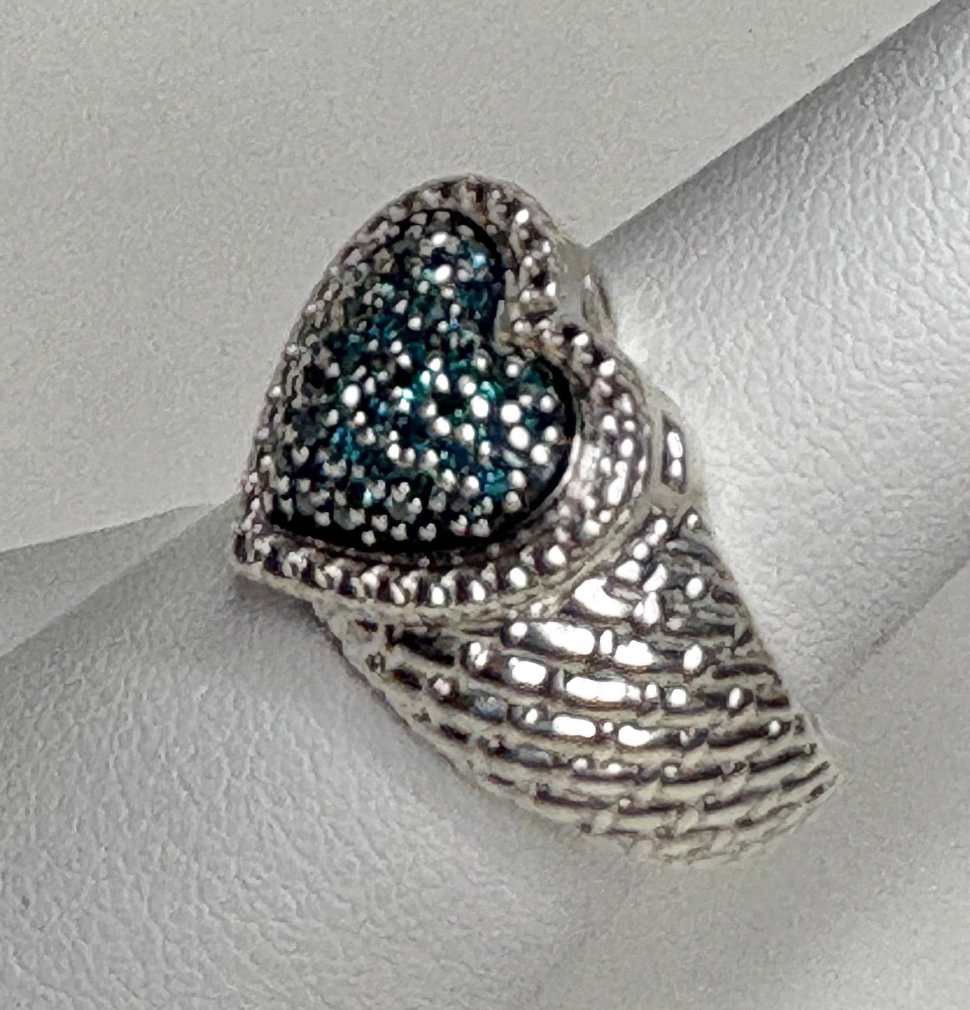 Sterling silver ring with a pave blue diamond heart and quilted band.