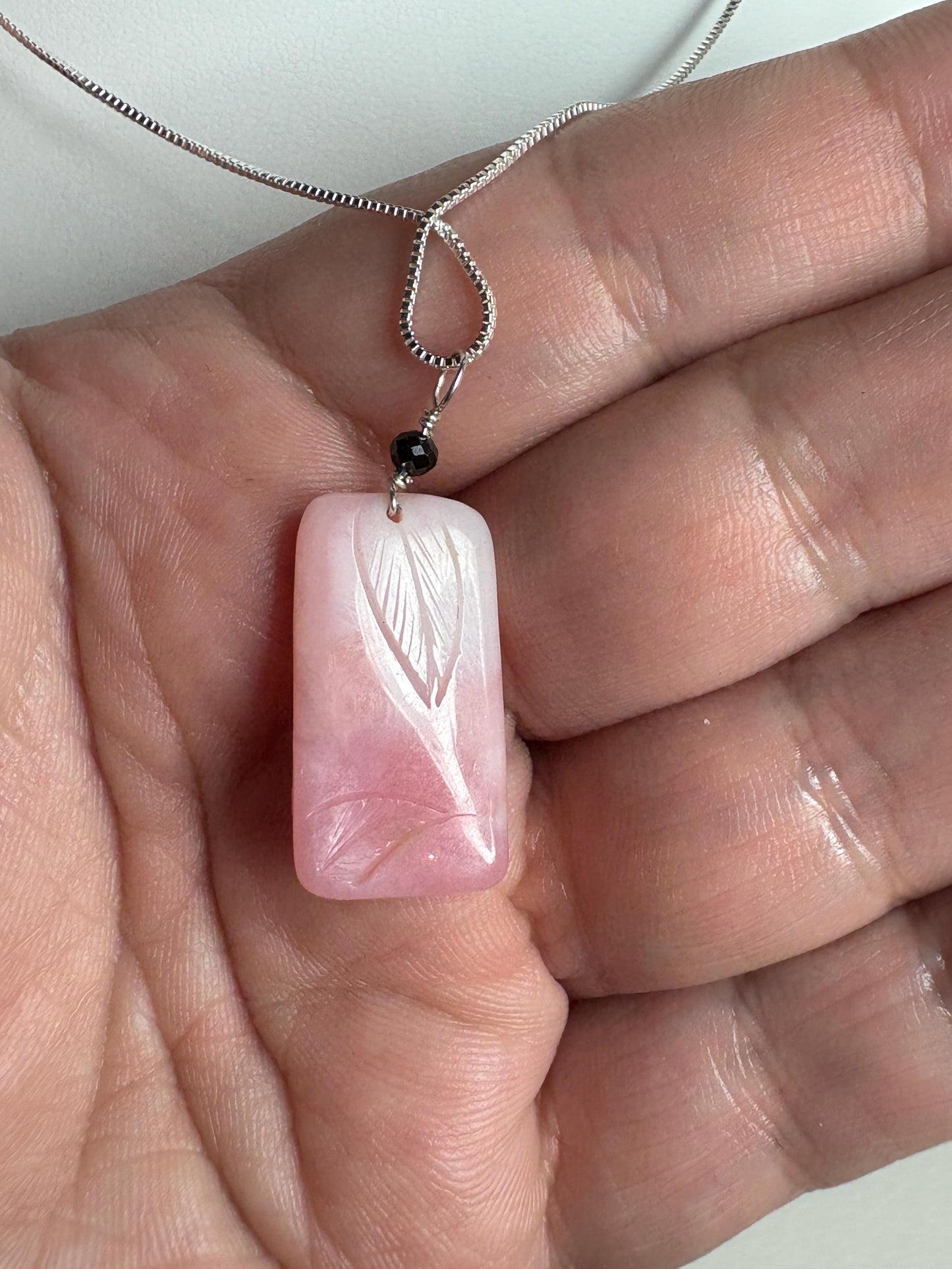 Carved Peruvian pink opal pendant with black diamond on sterling silver chain.