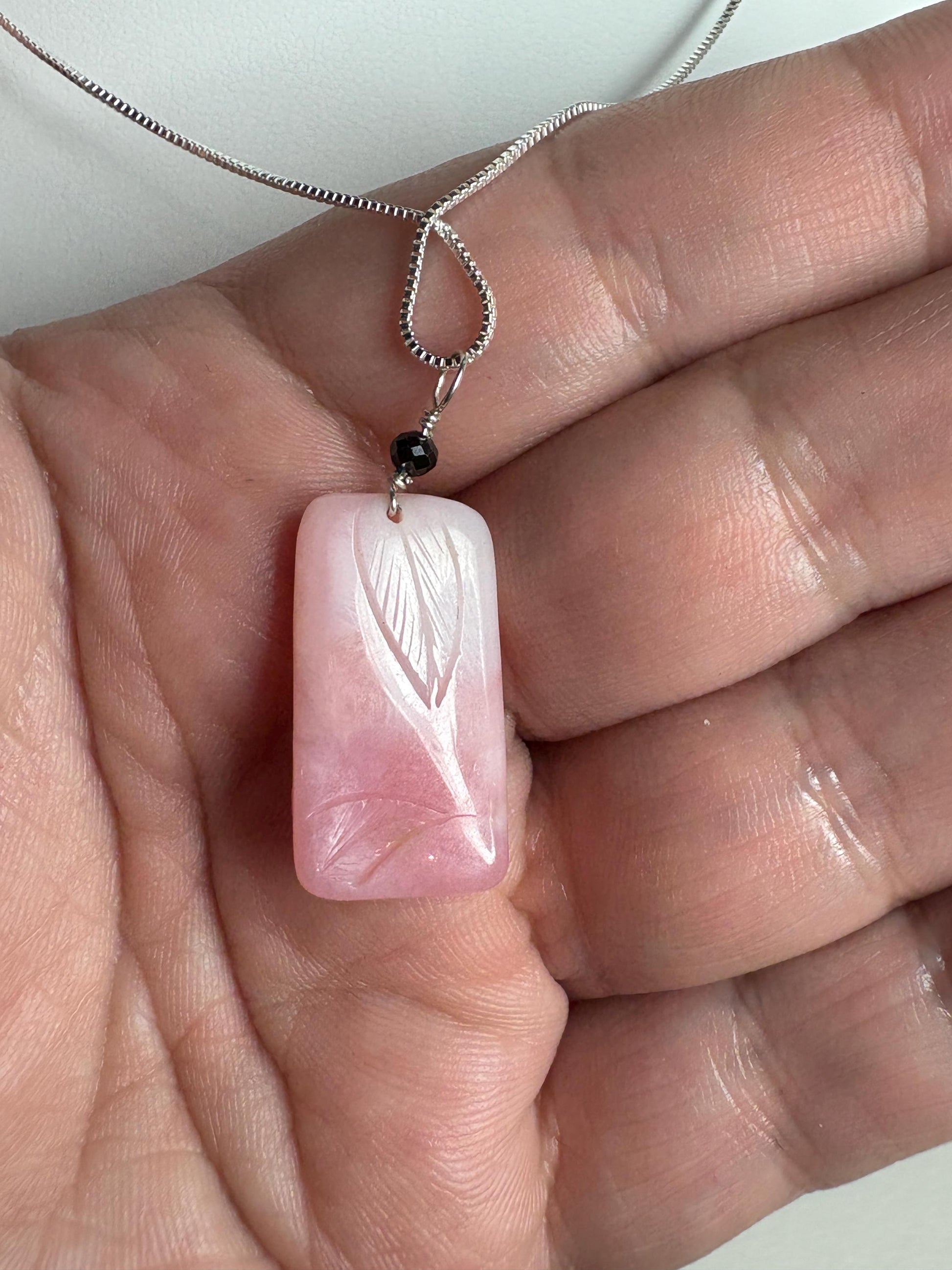Carved Peruvian pink opal pendant with black diamond on sterling silver chain.
