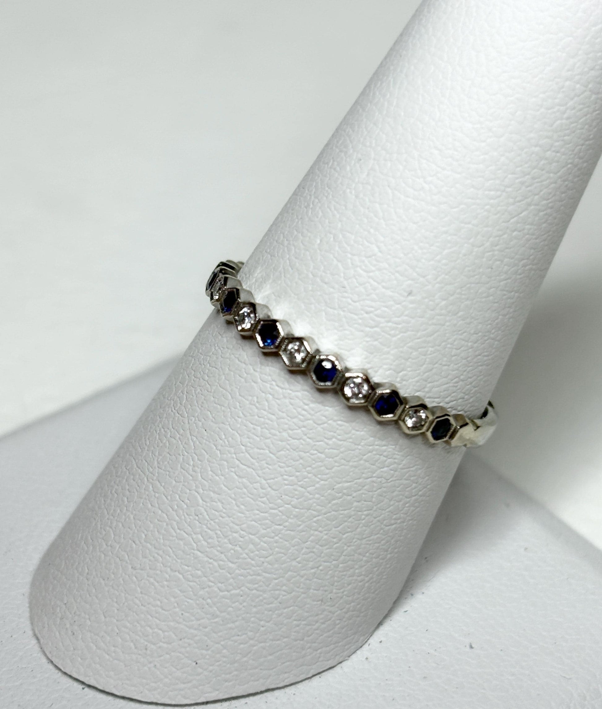 A 14k white gold band ring with alternating blue sapphires and diamonds in a honeycomb hexagon design.